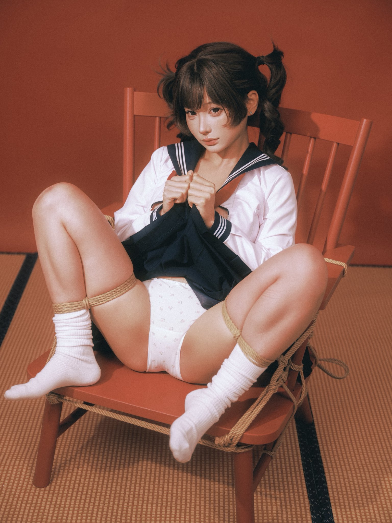 一位穿着蓝色衬衫和白色裤子的女人坐在红色椅子上。