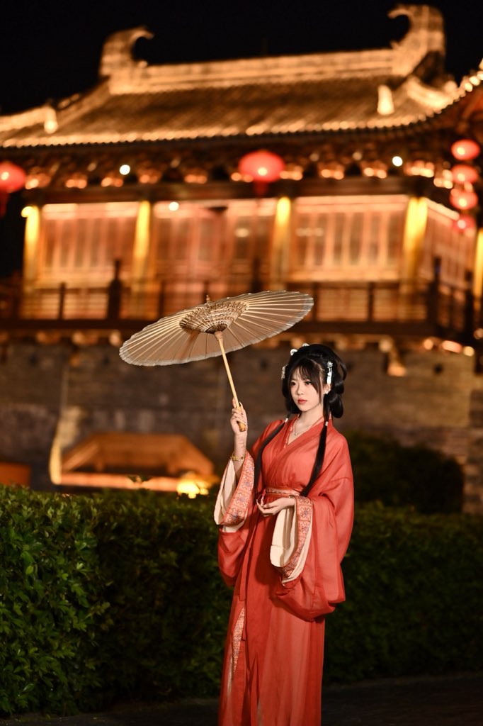 穿着红色裙子和发型装饰的女人坐在砖墙上。