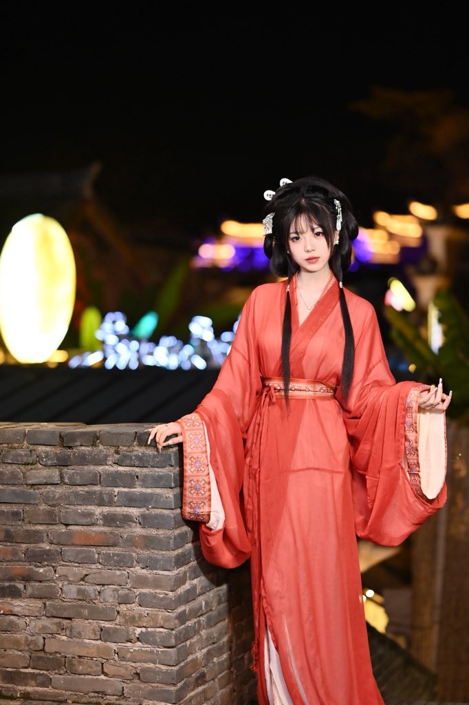 穿着红色裙子和发型装饰的女人坐在砖墙上。