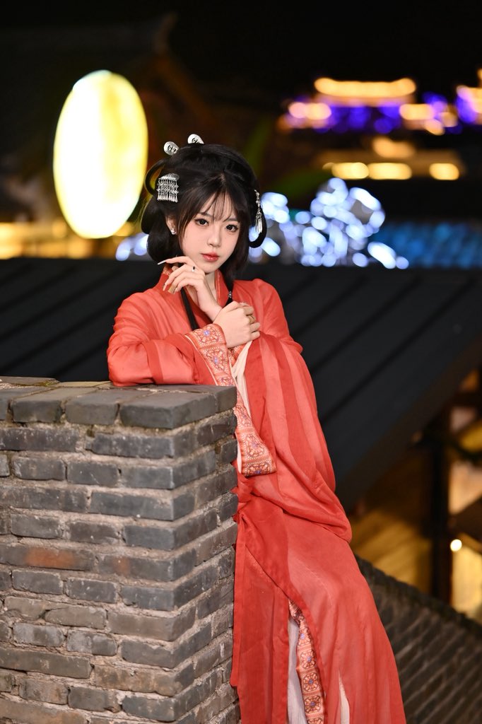 穿着红色裙子和发型装饰的女人坐在砖墙上。