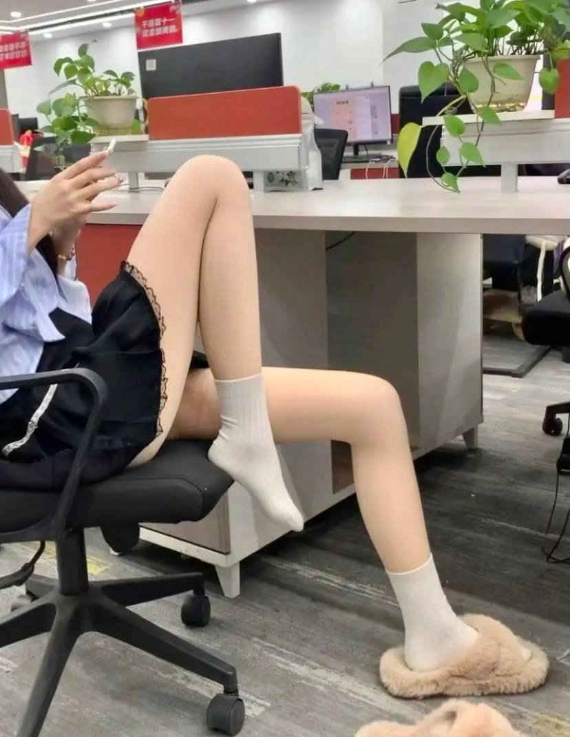 穿着黑色裙子和白色袜子的女人坐在椅子上。