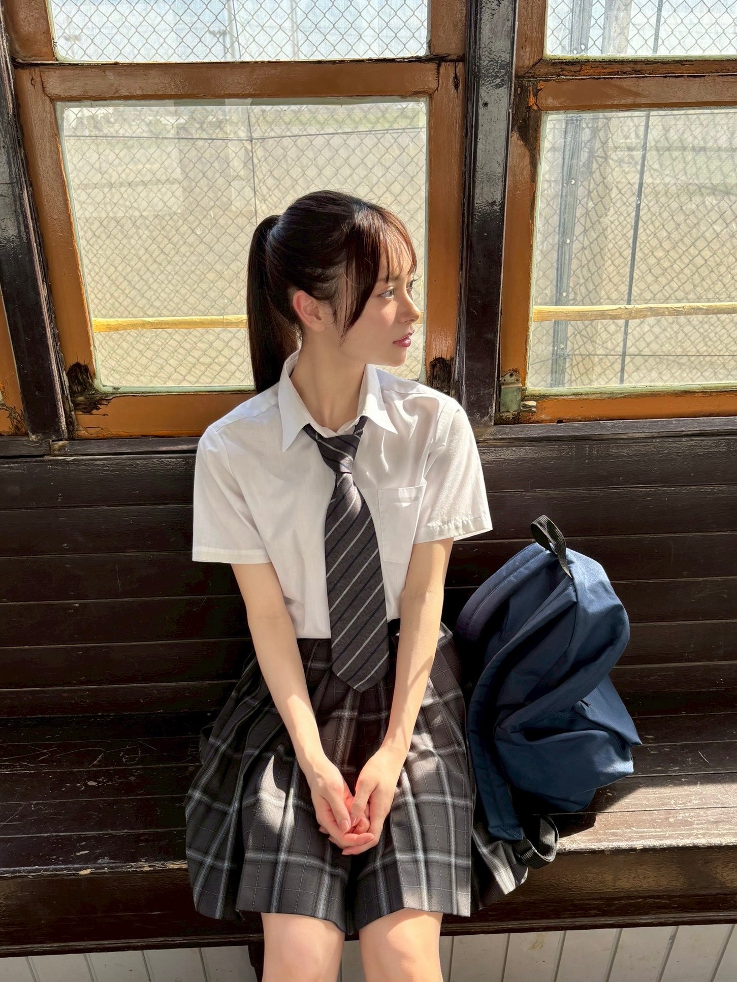 穿着衬衫的女孩坐在一个凳子上。