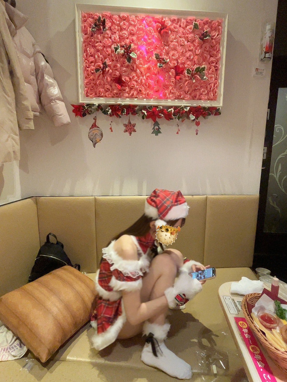 戴着圣诞老人的帽子的女人坐在沙发上,看着她的手机。