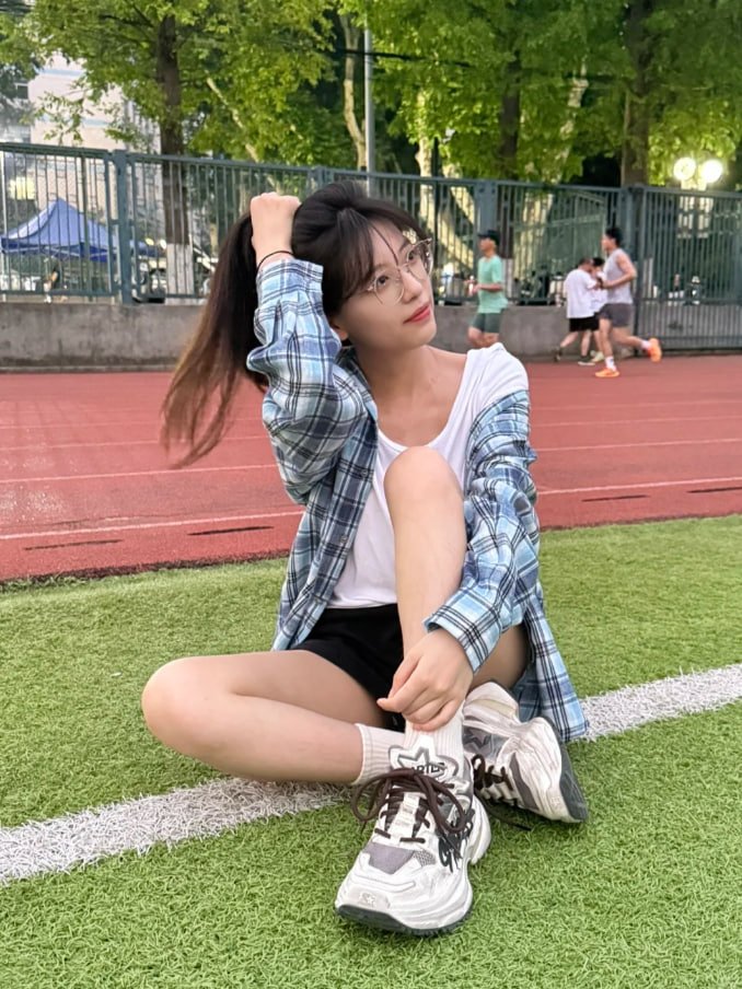 穿着的衬衫的女人坐在草地上吃饭。