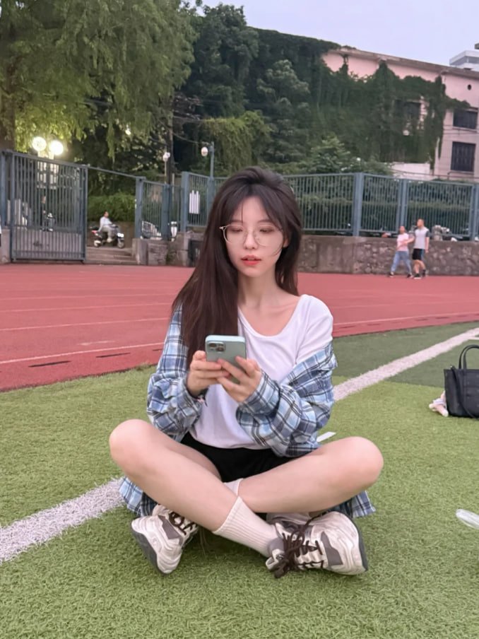 穿着的衬衫的女人坐在草地上吃饭。