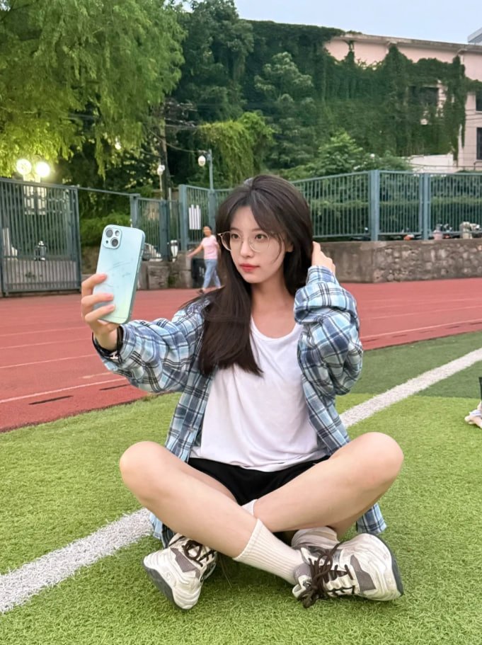 穿着的衬衫的女人坐在草地上吃饭。