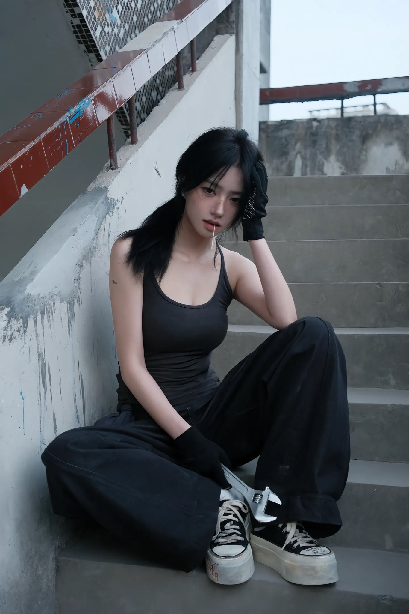 穿着黑色衬衫和黑裤子的女人坐在楼梯上。