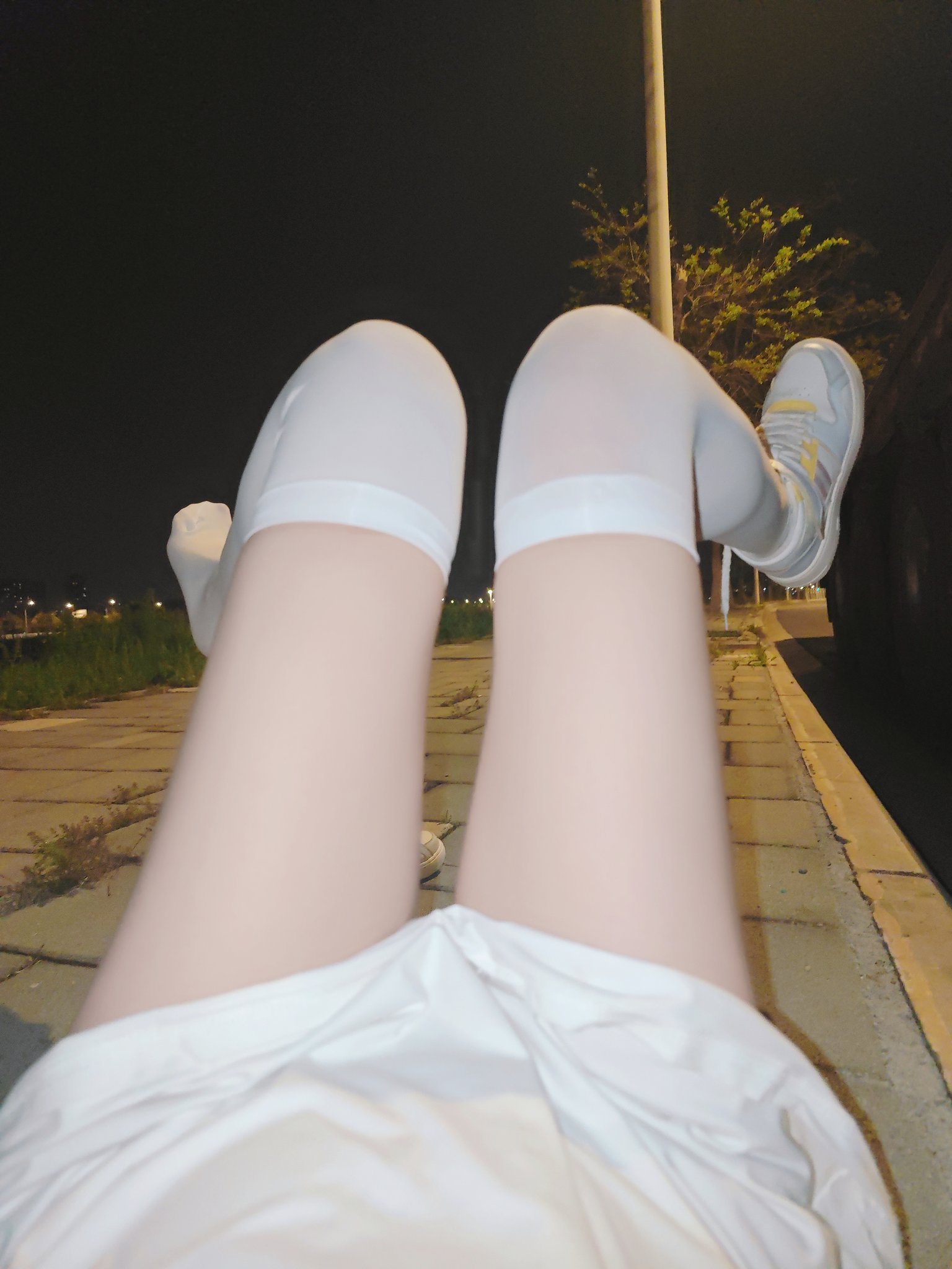 穿着白色袜子和白色裙子的女人坐在地上。