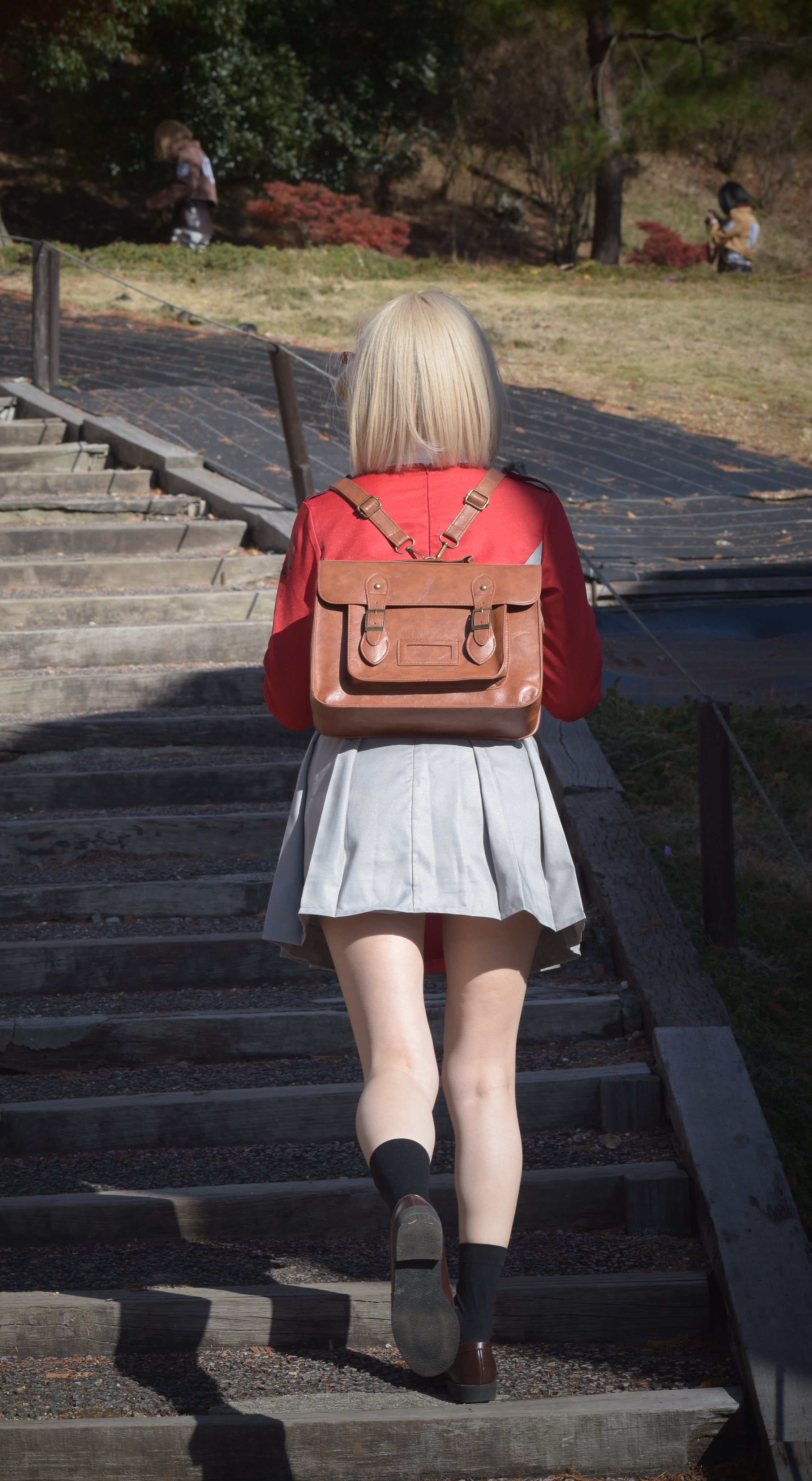 一位穿着红色外套和携带棕色袋子的女人走下楼梯。