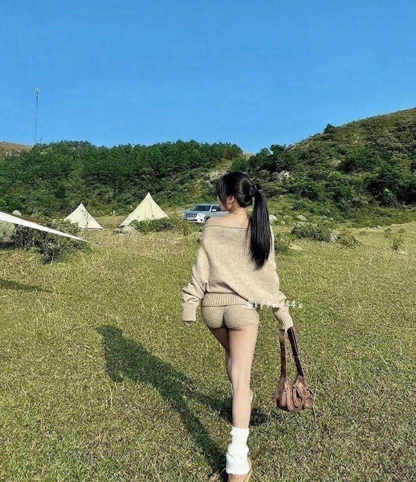 一位穿着白色衬衫的女人穿过一片草地。