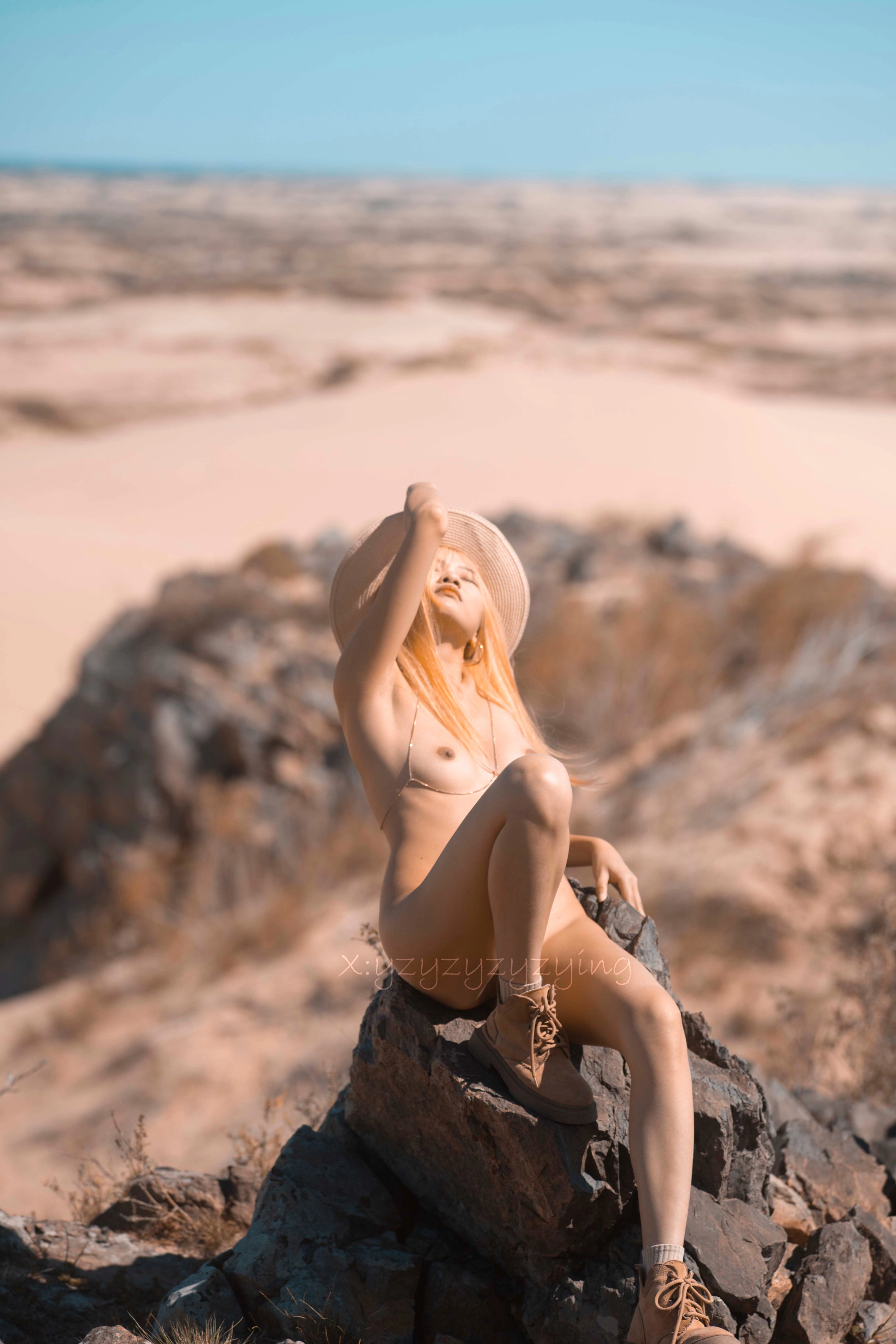 Người phụ nữ mặc mũ và cổ áo ngồi trên một tảng đá.