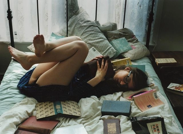 女人躺在床上,手里拿着一本书。