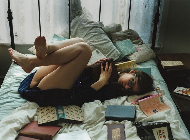 女人躺在床上,手里拿着一本书。