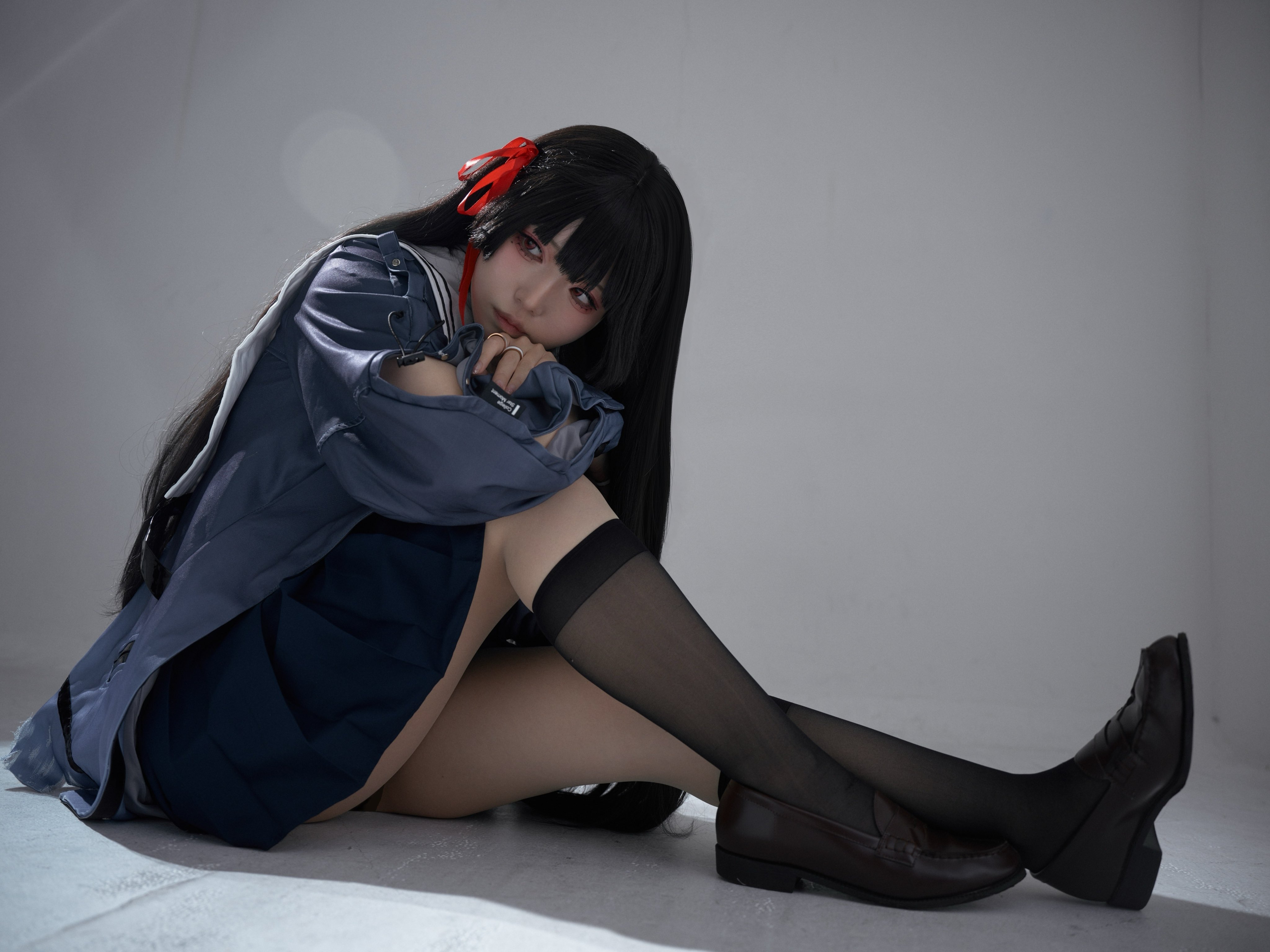 黑头发和红带的女孩坐在地板上。