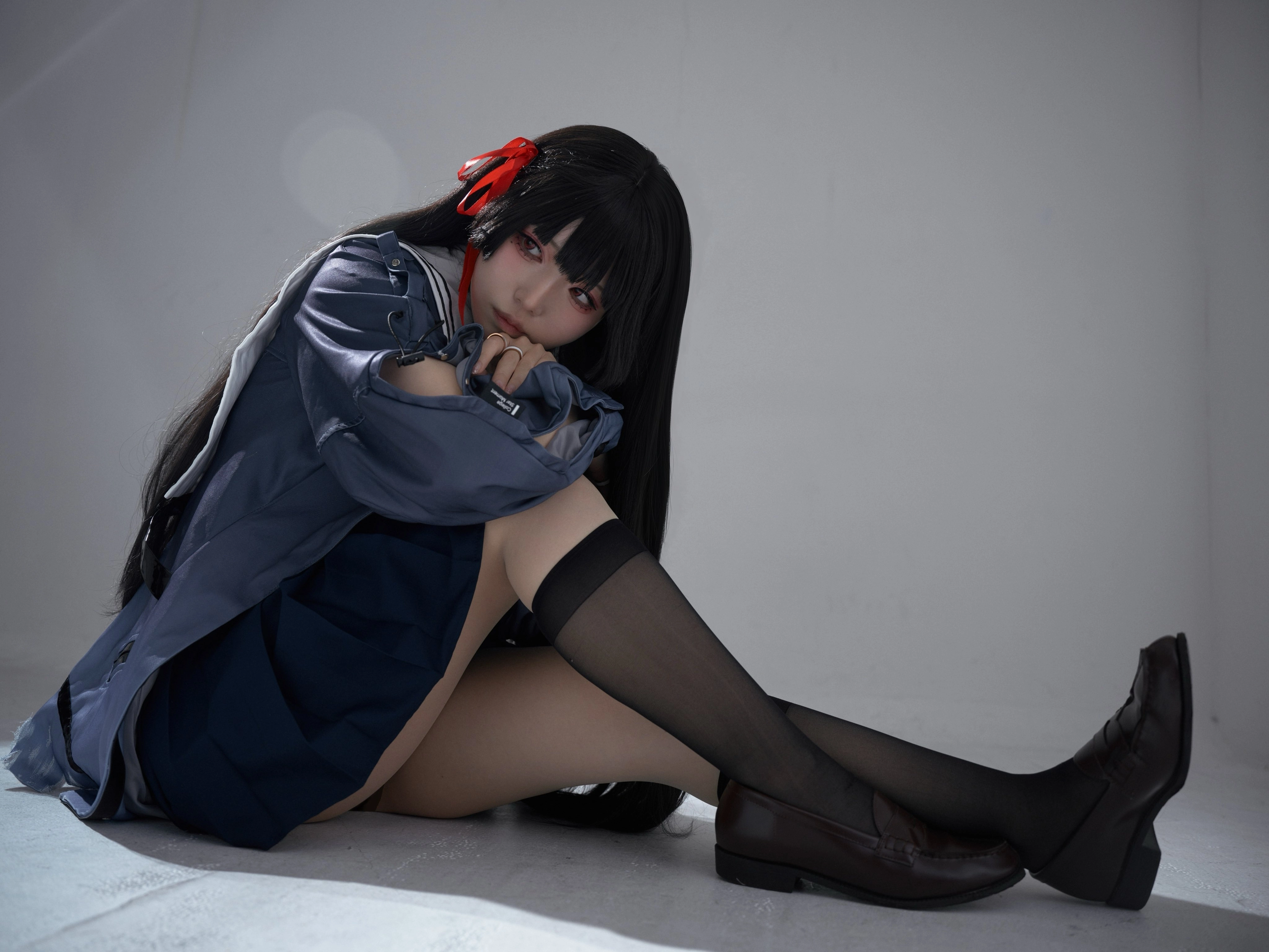 黑头发和红带的女孩坐在地板上。