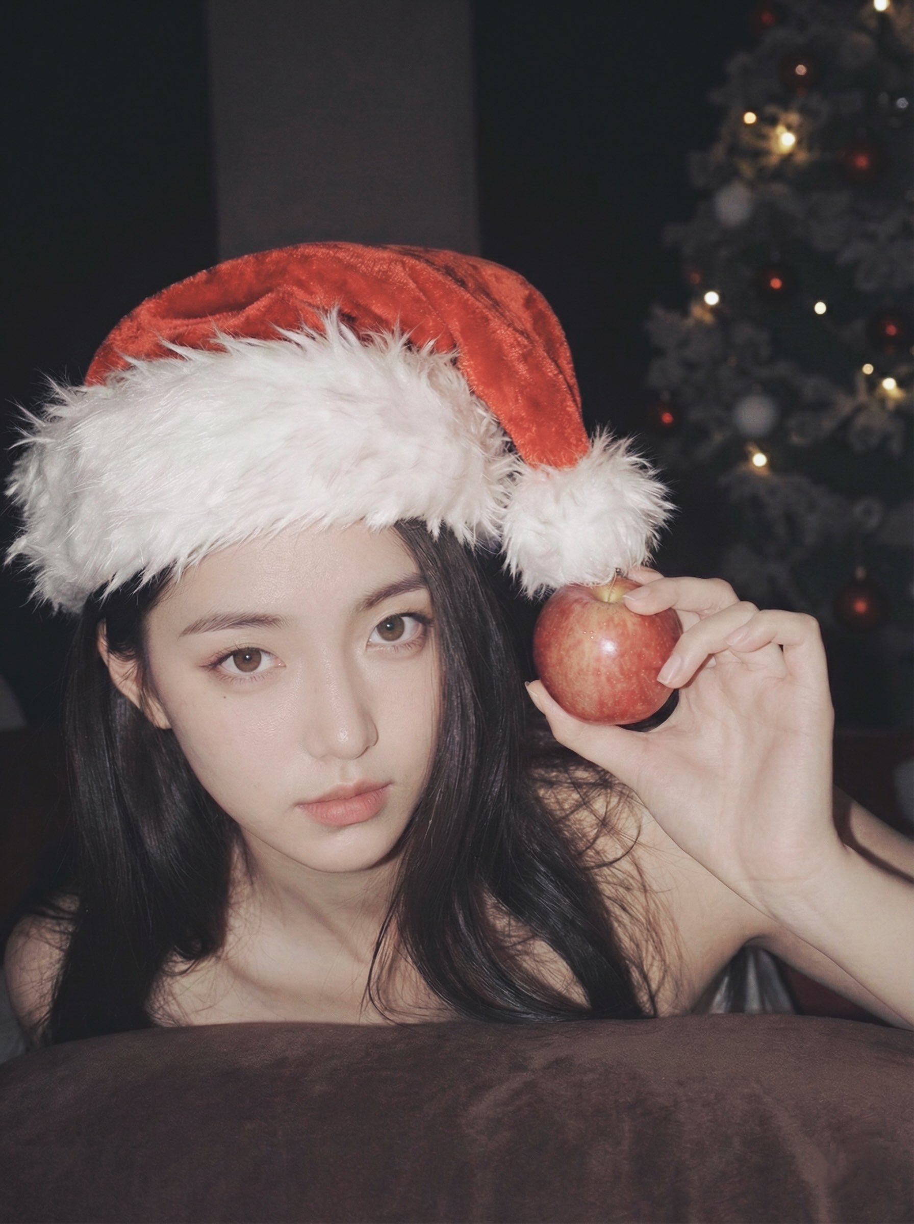 戴着圣诞老人帽子的女人拿着一颗苹果。