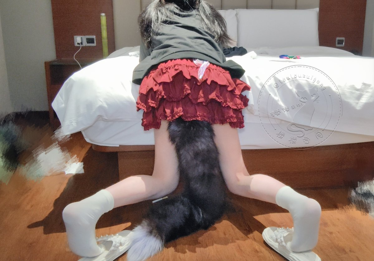 一位穿着黑色衬衫和红色裙子的女人坐在床上。