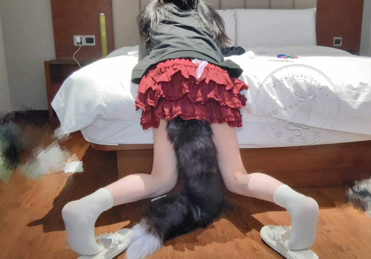 一位穿着黑色衬衫和红色裙子的女人坐在床上。