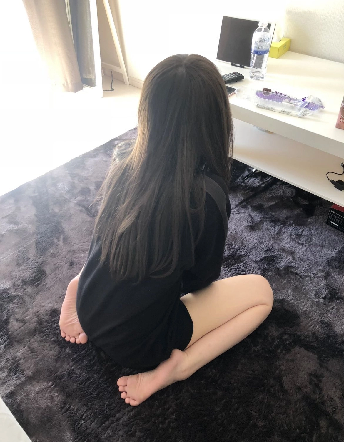 女人坐在电视机前的地毯上。