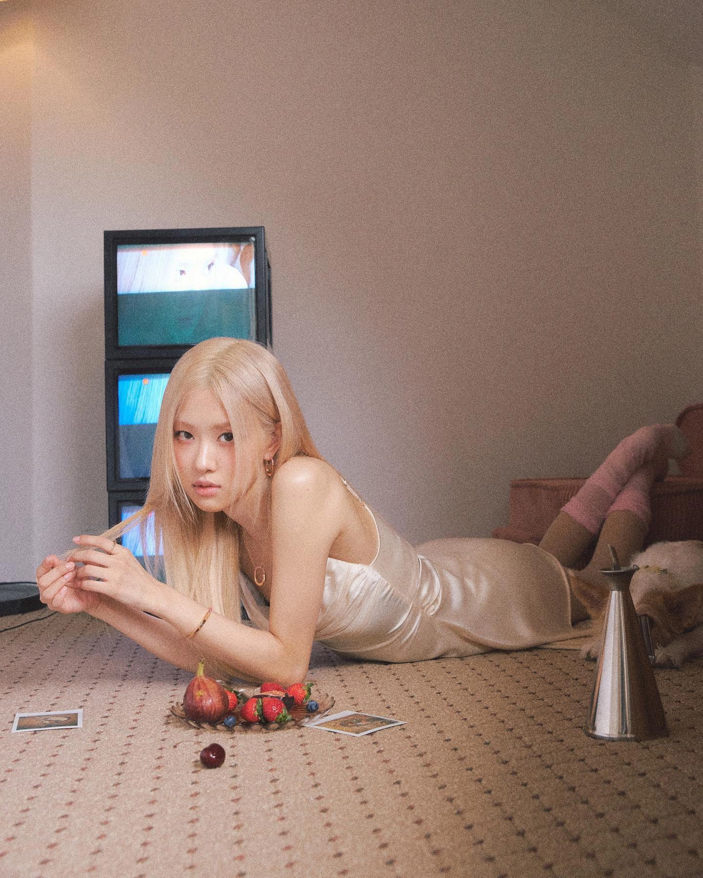 金发的女人躺在地板上,她面前有一盘水果。