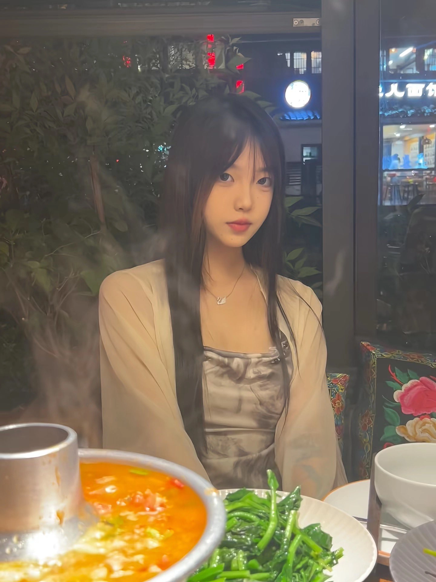 长头发和项链的女人坐在一张桌子上。