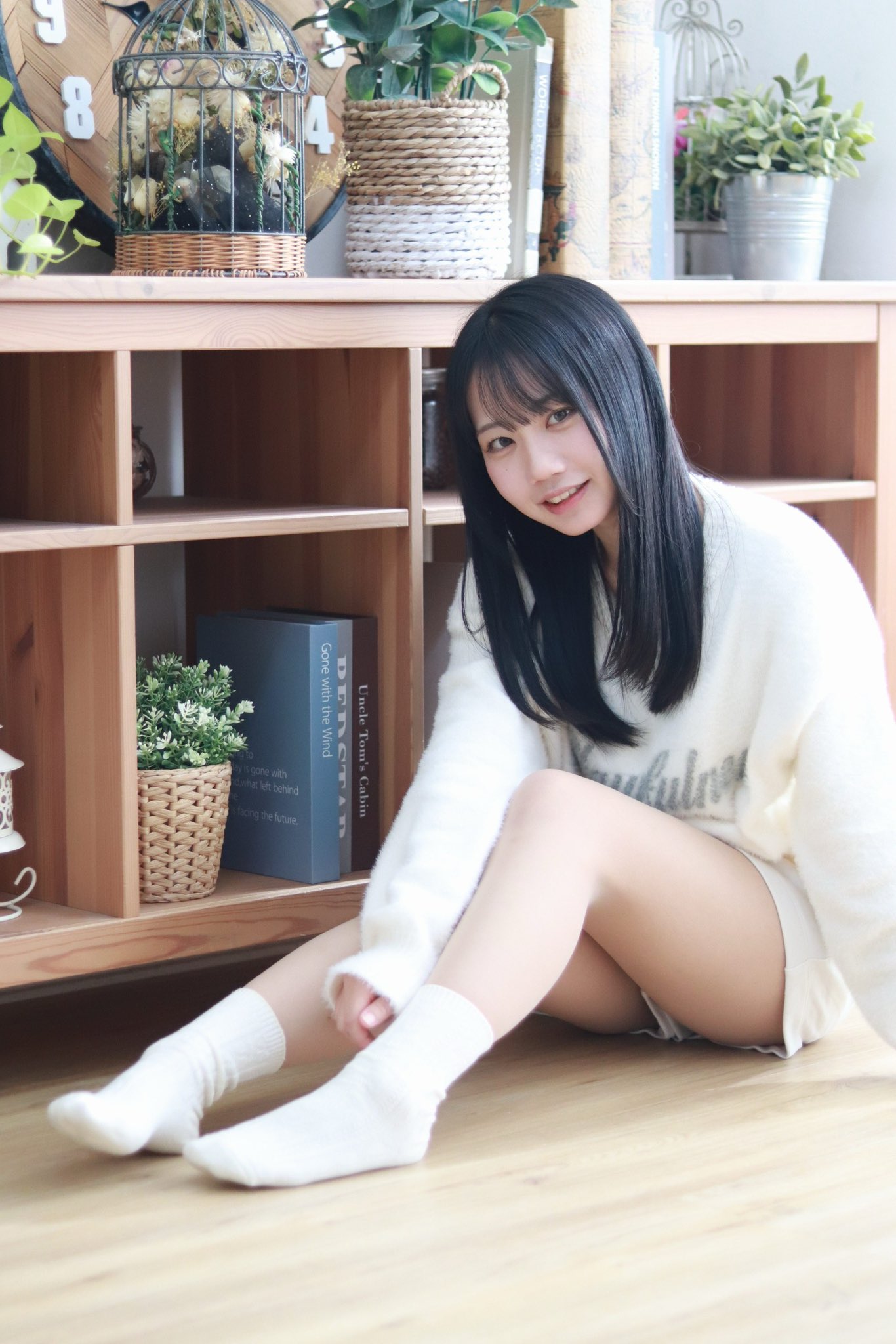 女人坐在书架前面的地板上。