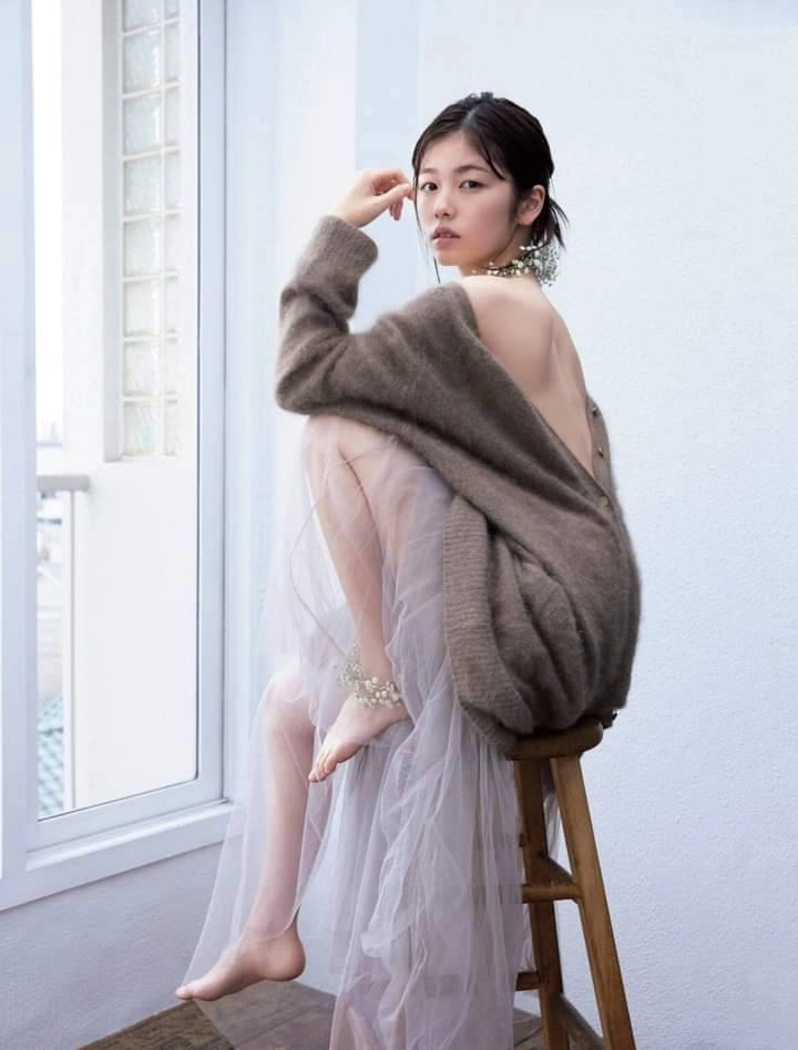 穿着灰色衬衫和白色裙子的女人坐在椅子上。