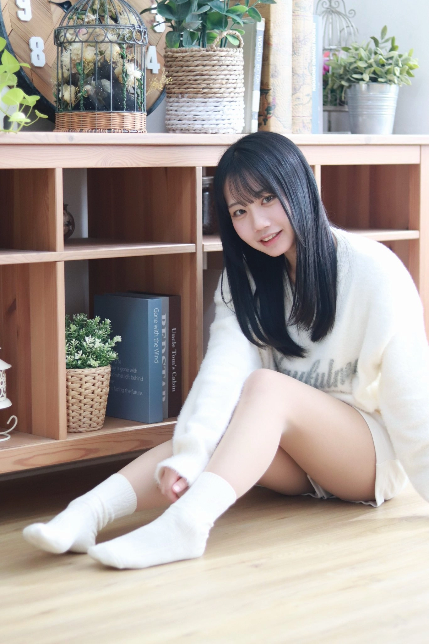 女人坐在书架前面的地板上。