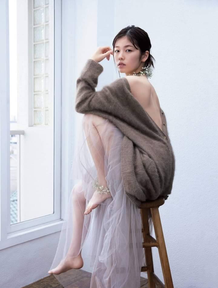 穿着灰色衬衫和白色裙子的女人坐在椅子上。