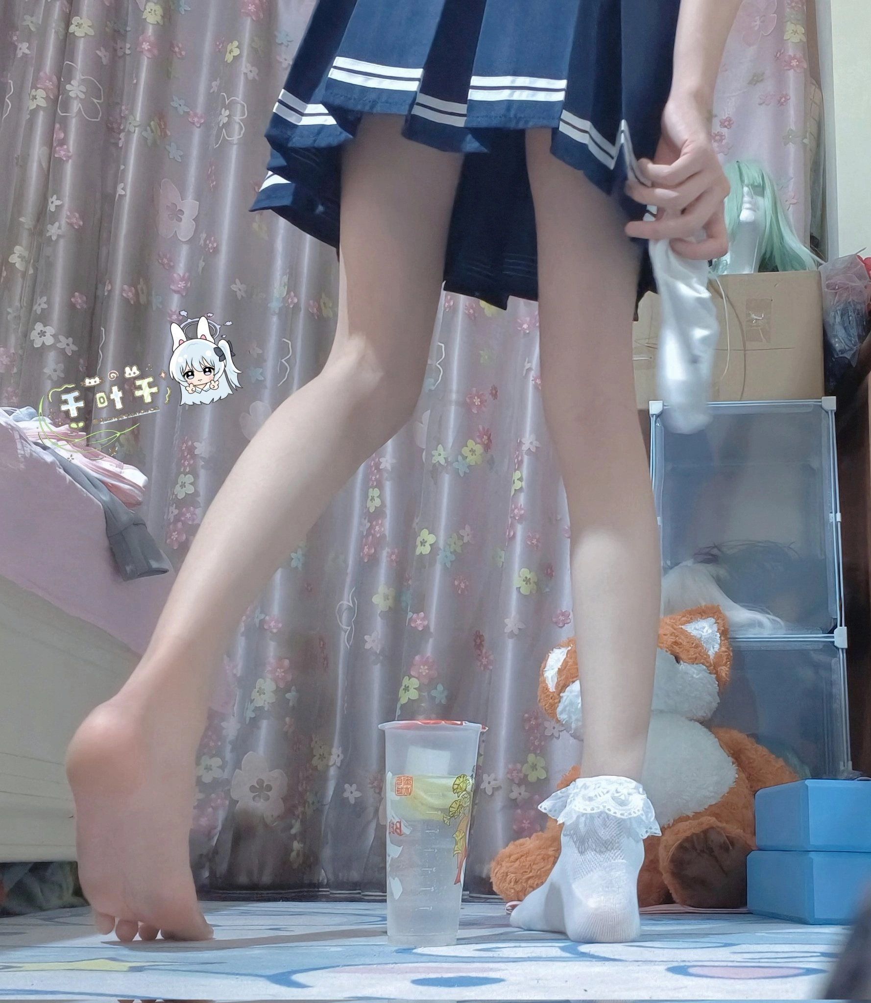 一位穿着蓝色衣服的女孩站在一间房间里,带着一只被填满的动物和一杯。