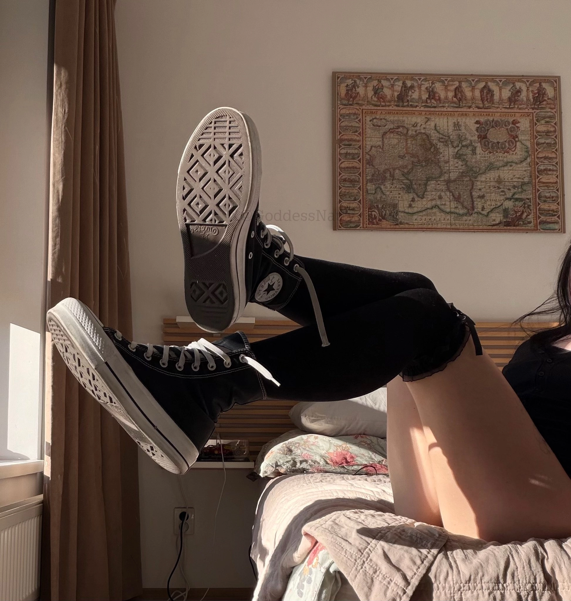 穿黑袜子和黑鞋的女人坐在床上。