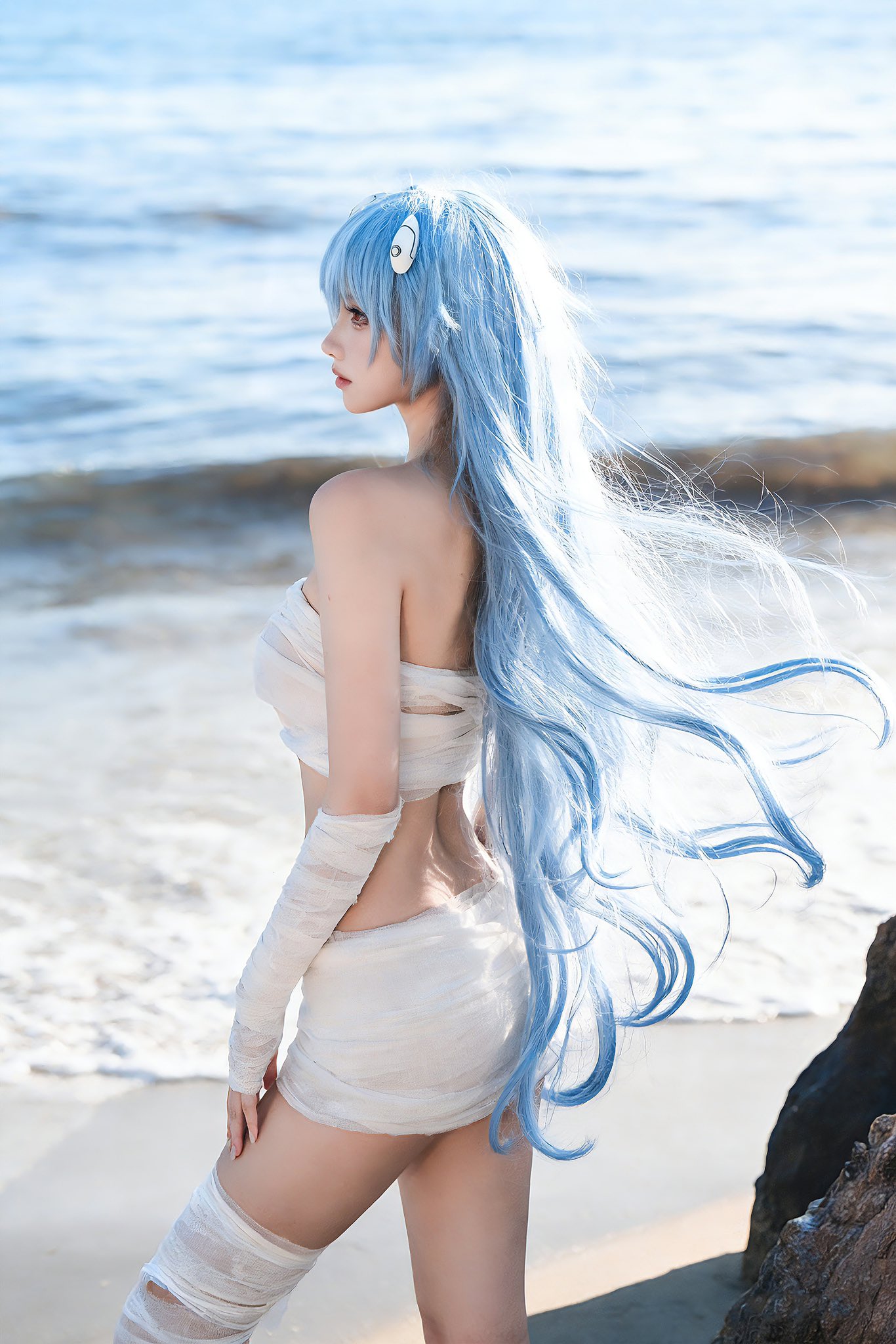 蓝头发的女人坐在海滩上。