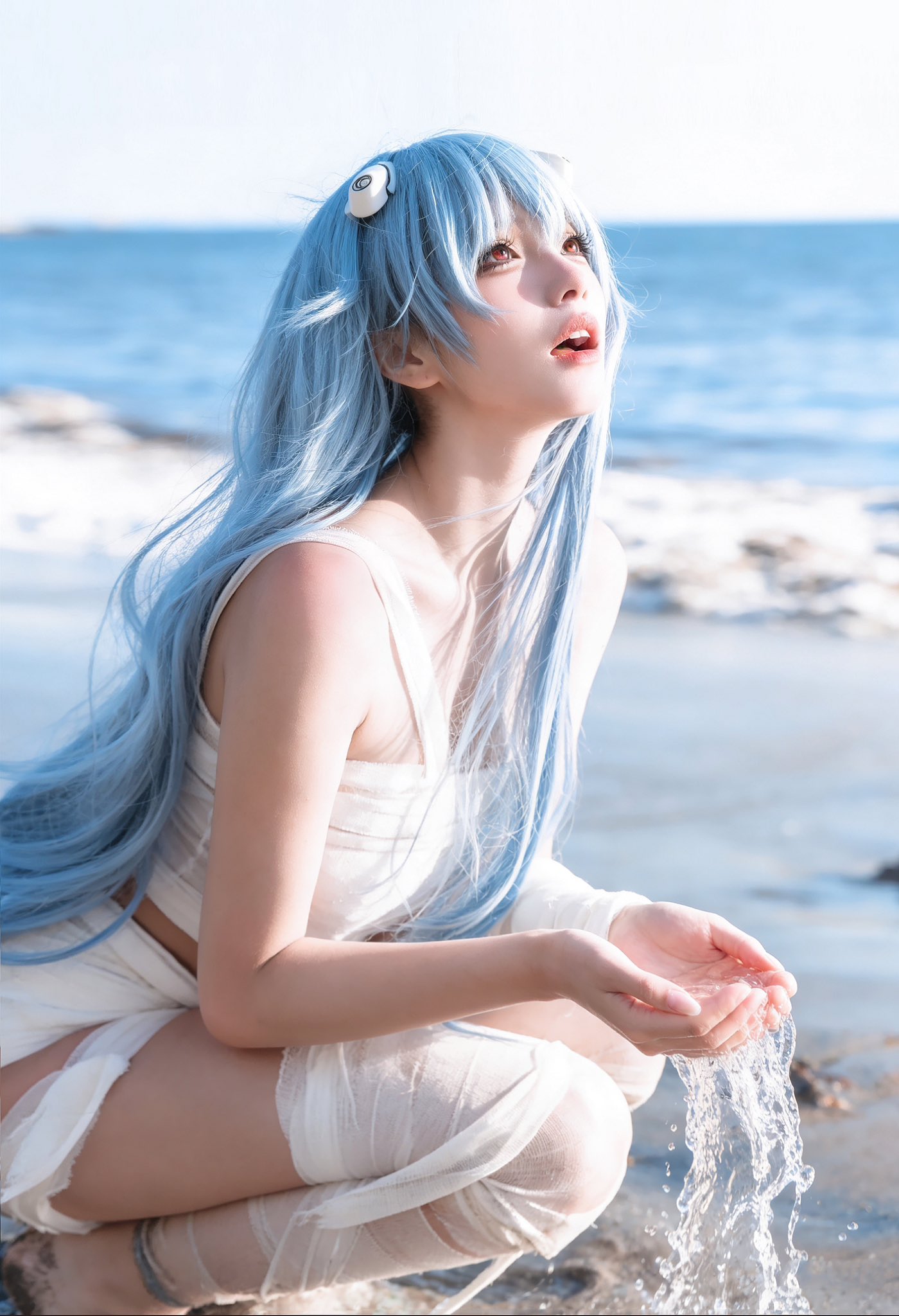 蓝头发的女人坐在海滩上。