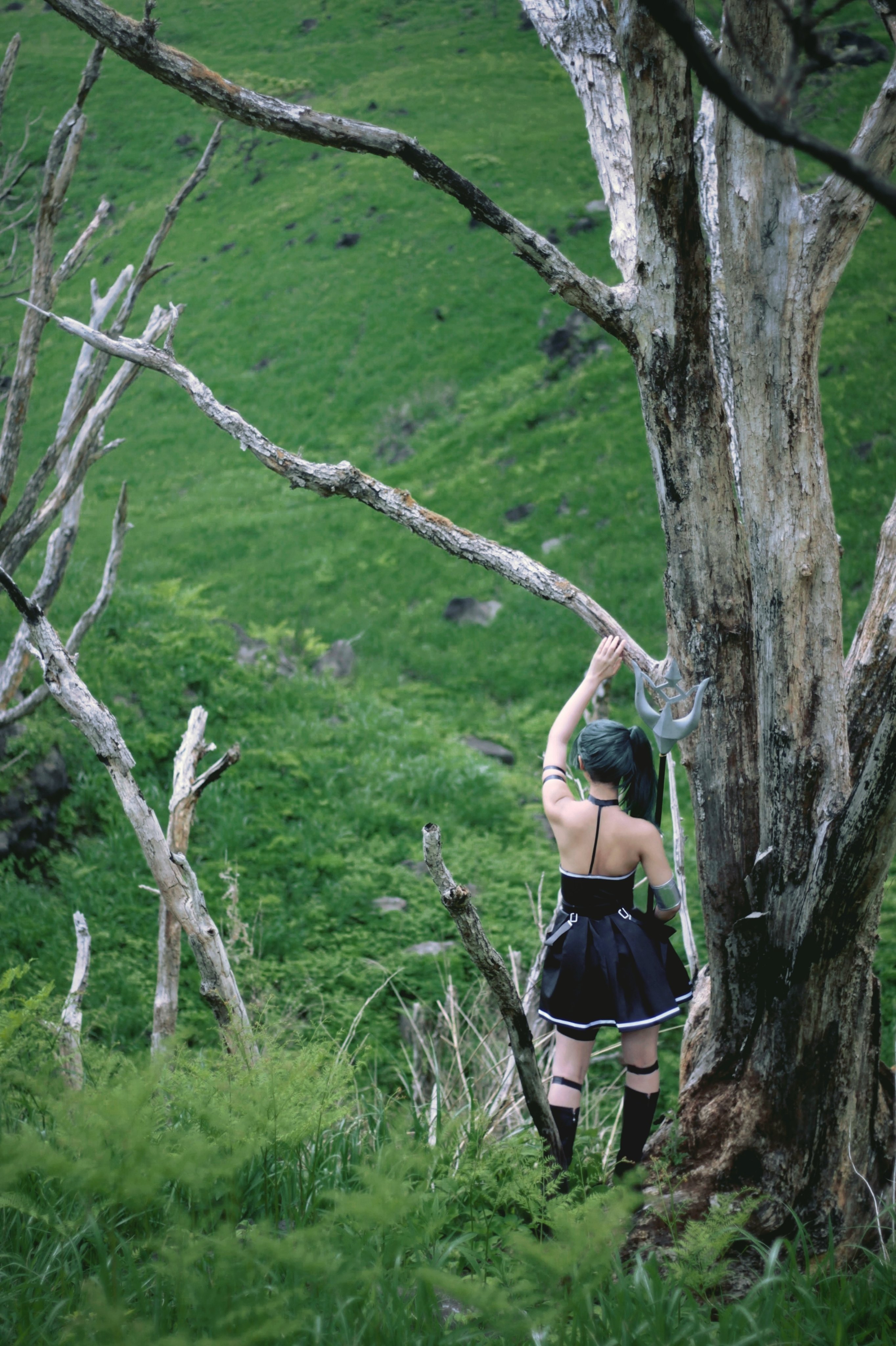 穿着黑色衣服的女人站在一棵树前。