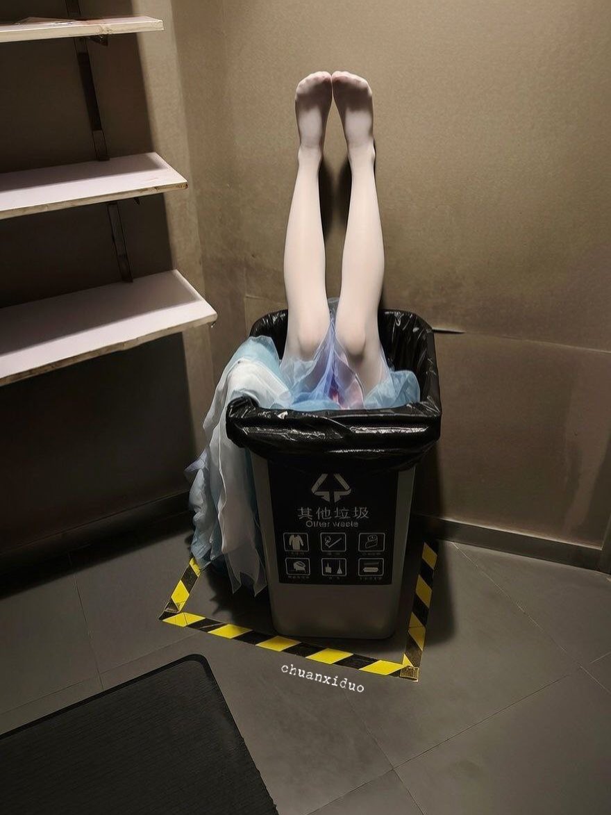 一位穿着蓝色礼服的女人躺在地板上,旁边是垃圾桶。