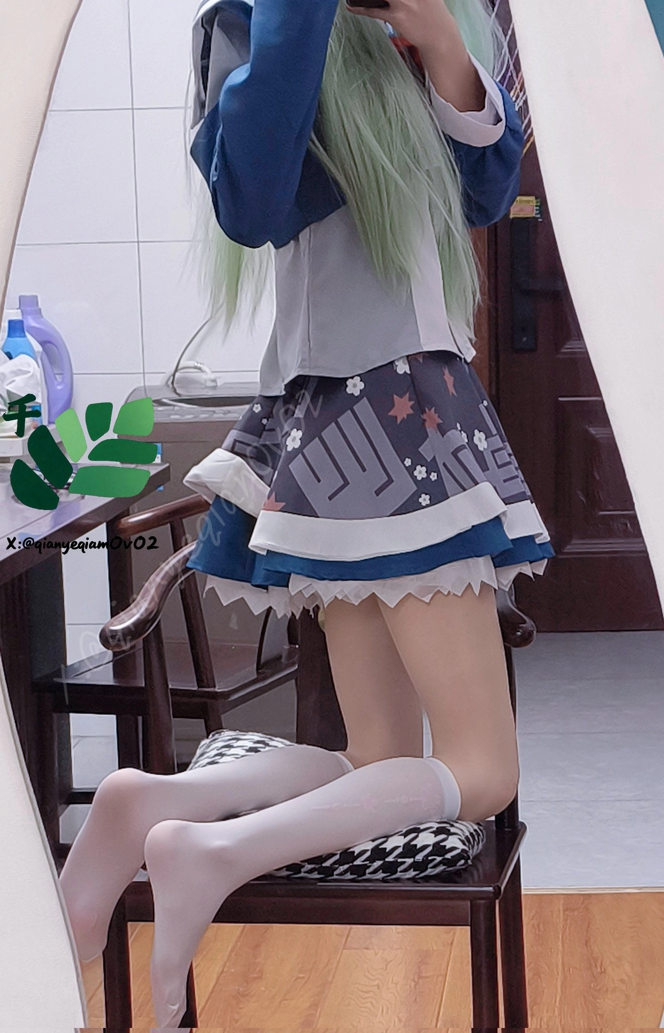 一位穿着蓝色裙子和白色袜子的女人坐在镜子前的椅子上。