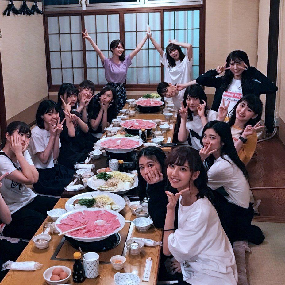 一群人坐在一张桌子周围,想拍一张照片。