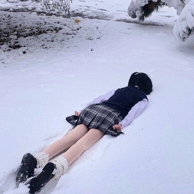 一位穿着黑色帽子和蓝色裙子的女人躺在雪地里。