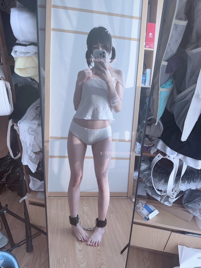 一位穿着白色衬衫和白色内衣的女人站在镜子前。