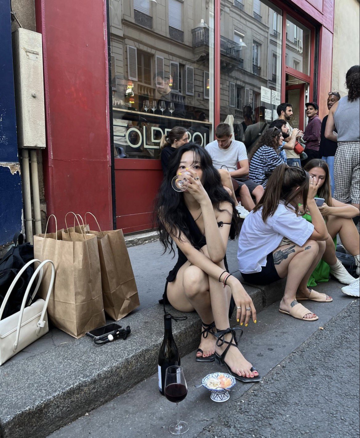 黑头发的女人坐在地上,拿着一杯酒。