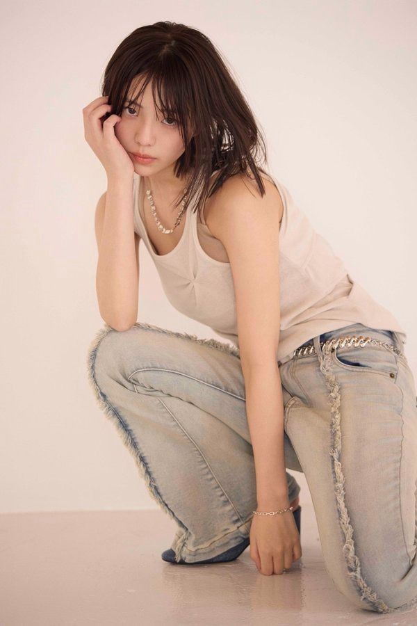 一位女人穿着白色坦克顶部和牛仔裤。