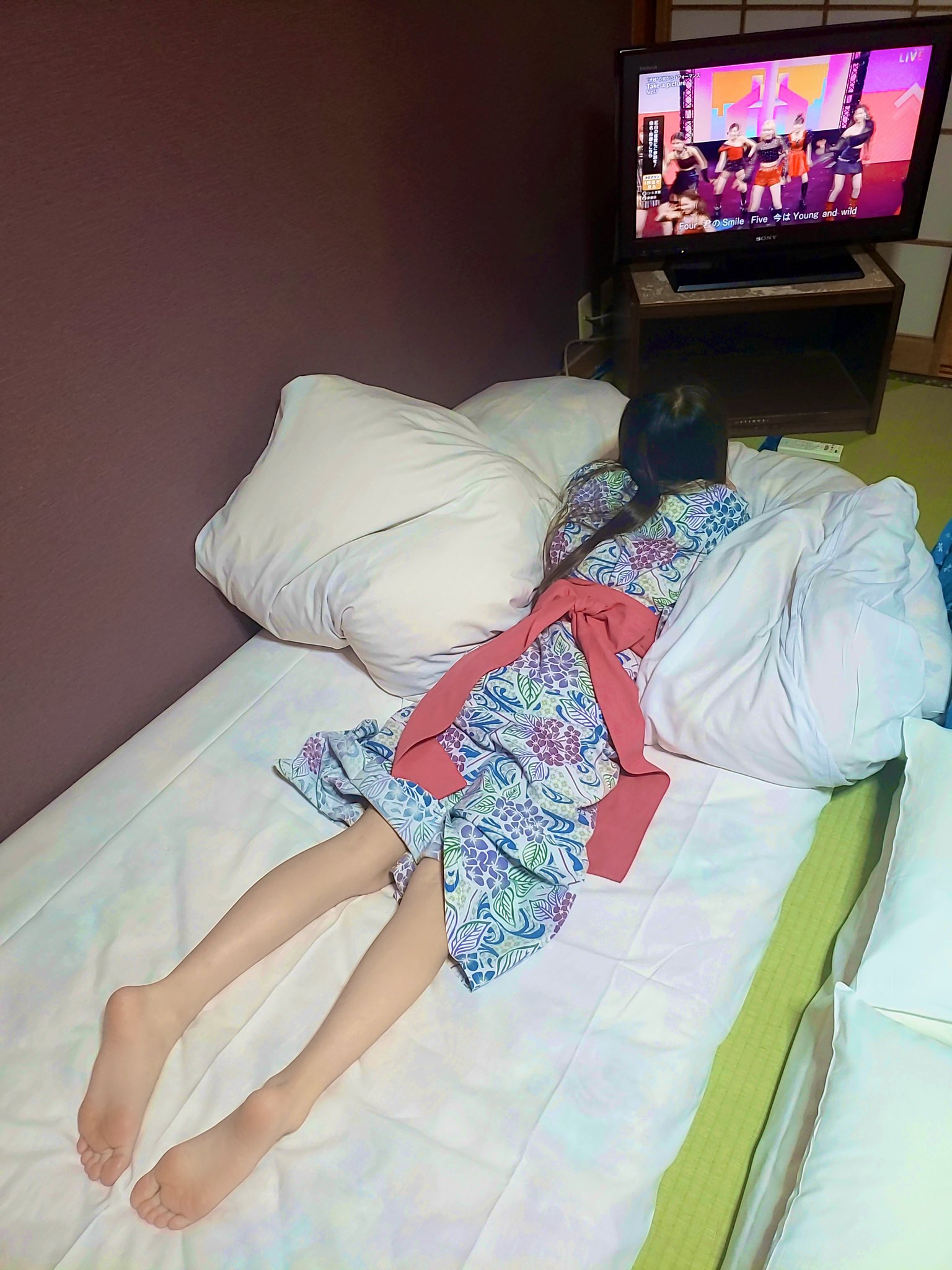 女人躺在床上看电视。