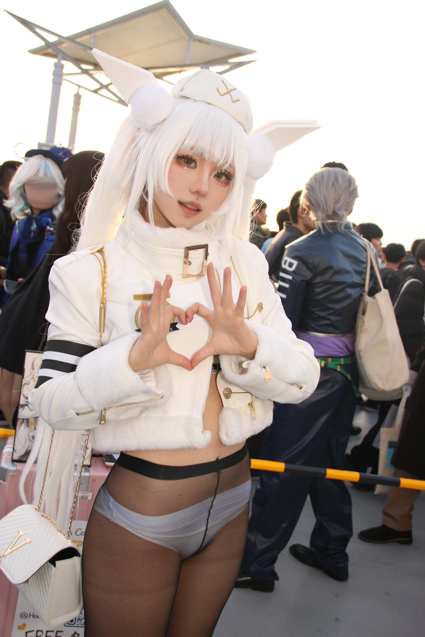 女人穿着一个白色的心脏形状的项链和一个白色的夹克。