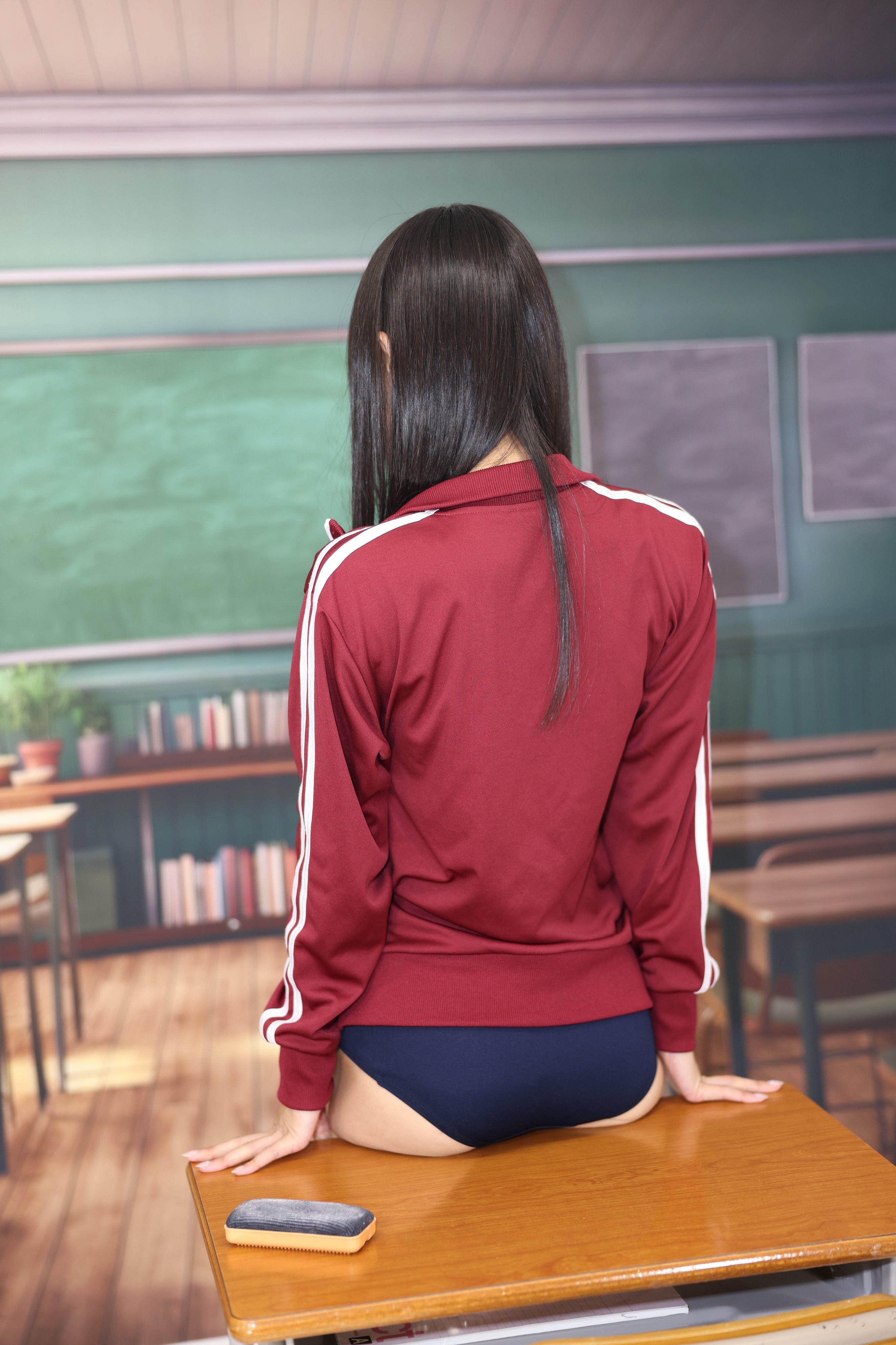 一位穿着红色夹克和蓝色短裤的女人站在一张板前面。