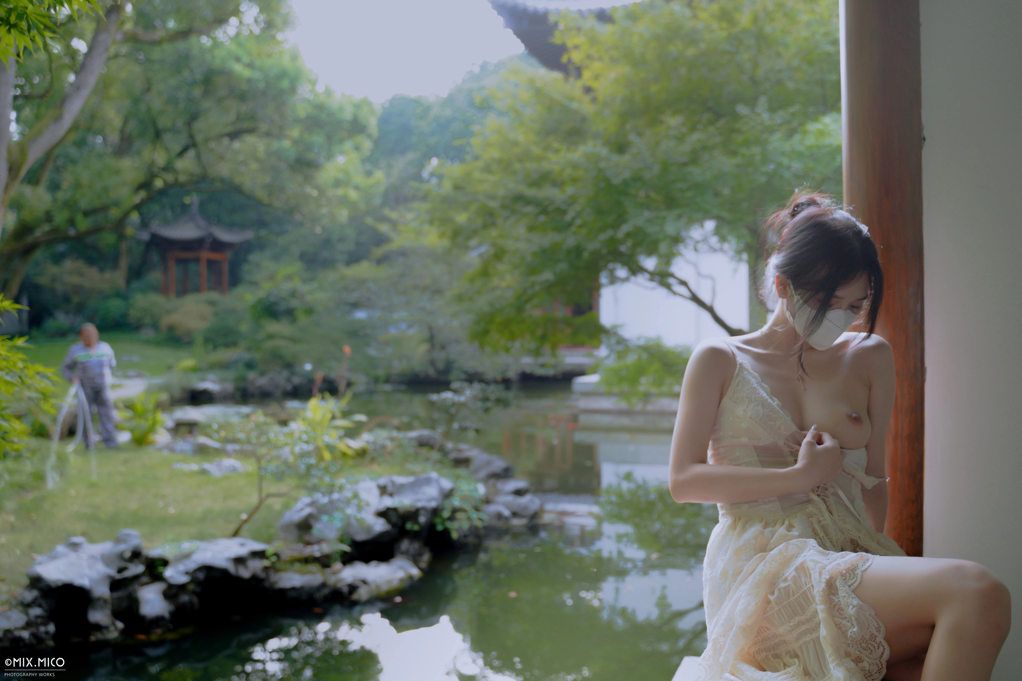 Người phụ nữ đeo mặt nạ ngồi bên hồ.