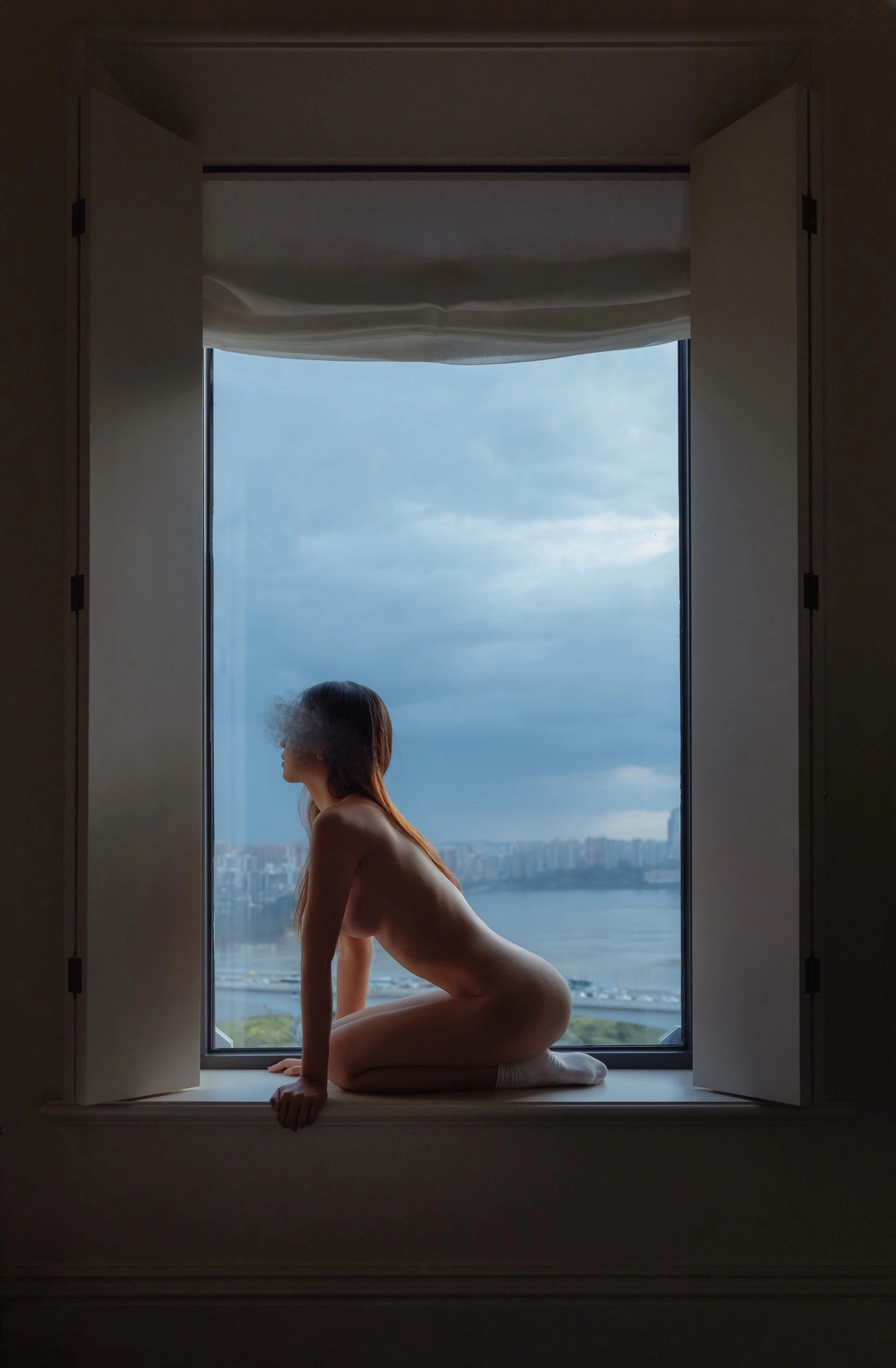 Người phụ nữ khỏa thân ngồi trước cửa sổ.