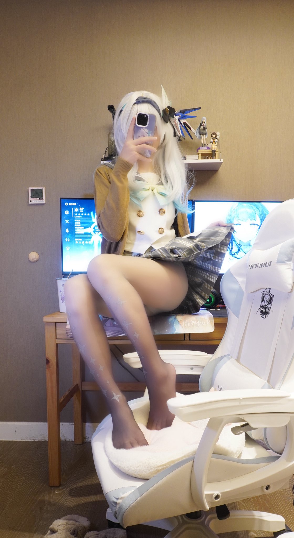 一位穿着白毛衣和蓝色裙子的女人坐在电脑前的椅子上。