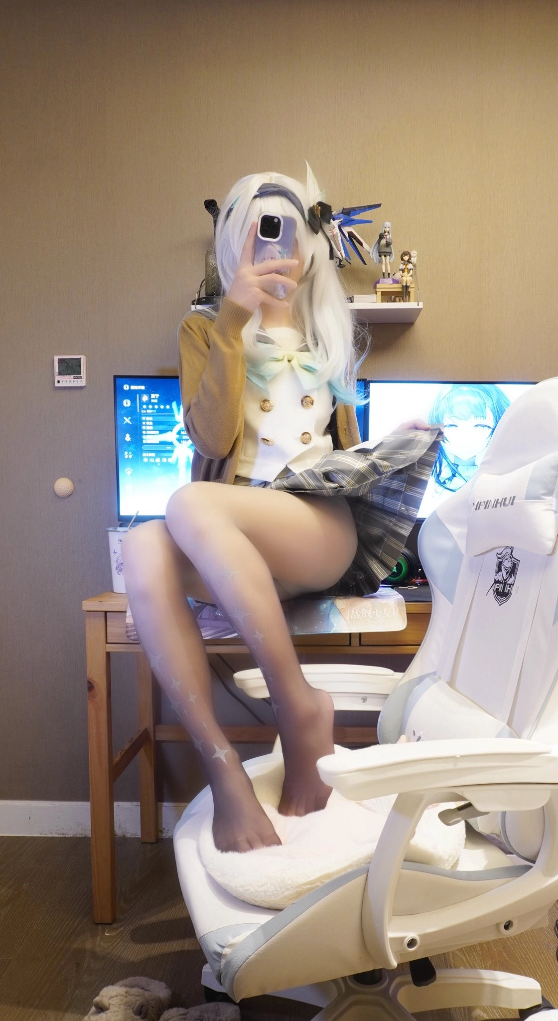 一位穿着白毛衣和蓝色裙子的女人坐在电脑前的椅子上。