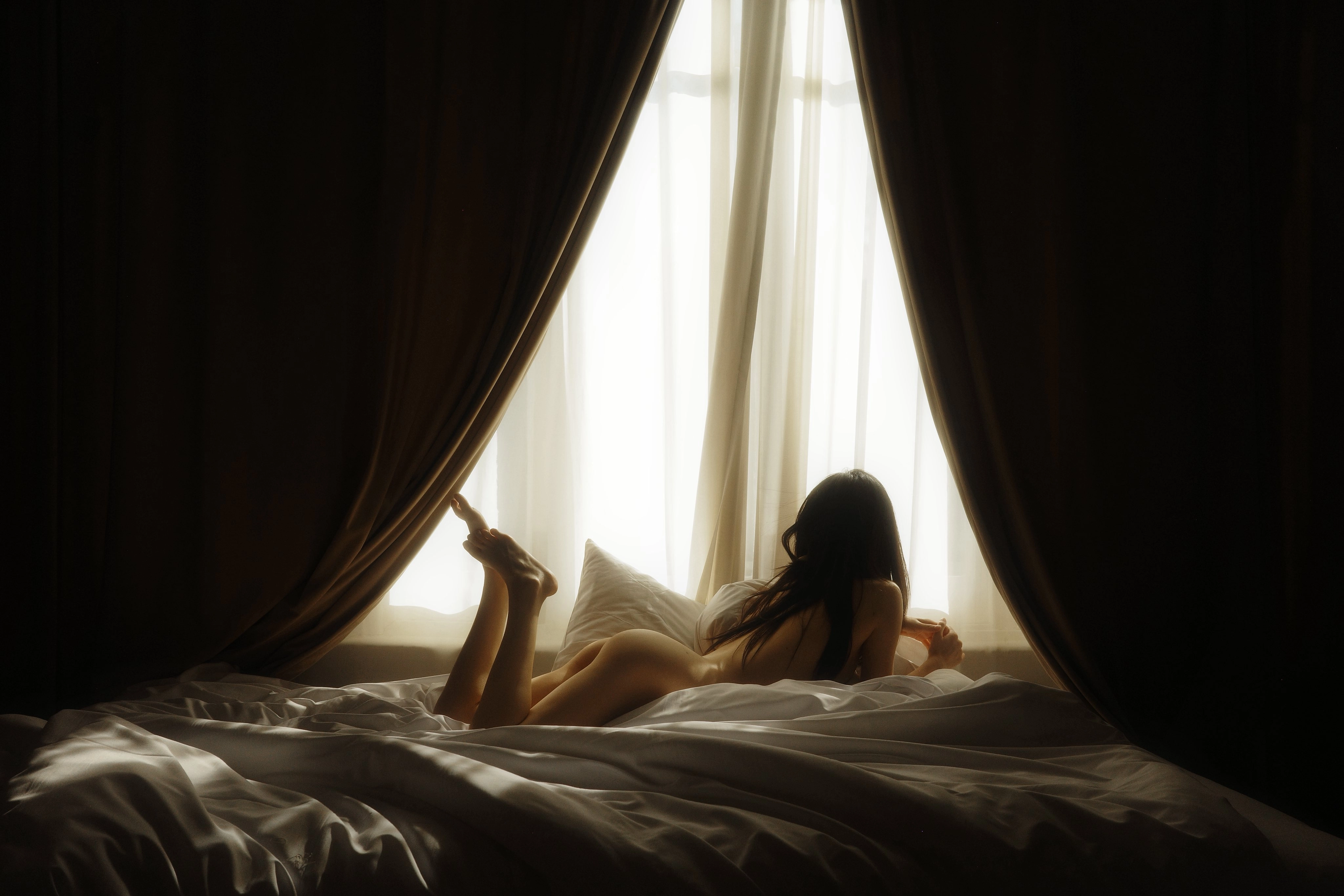 The woman lay on the bed, her legs stretched out.