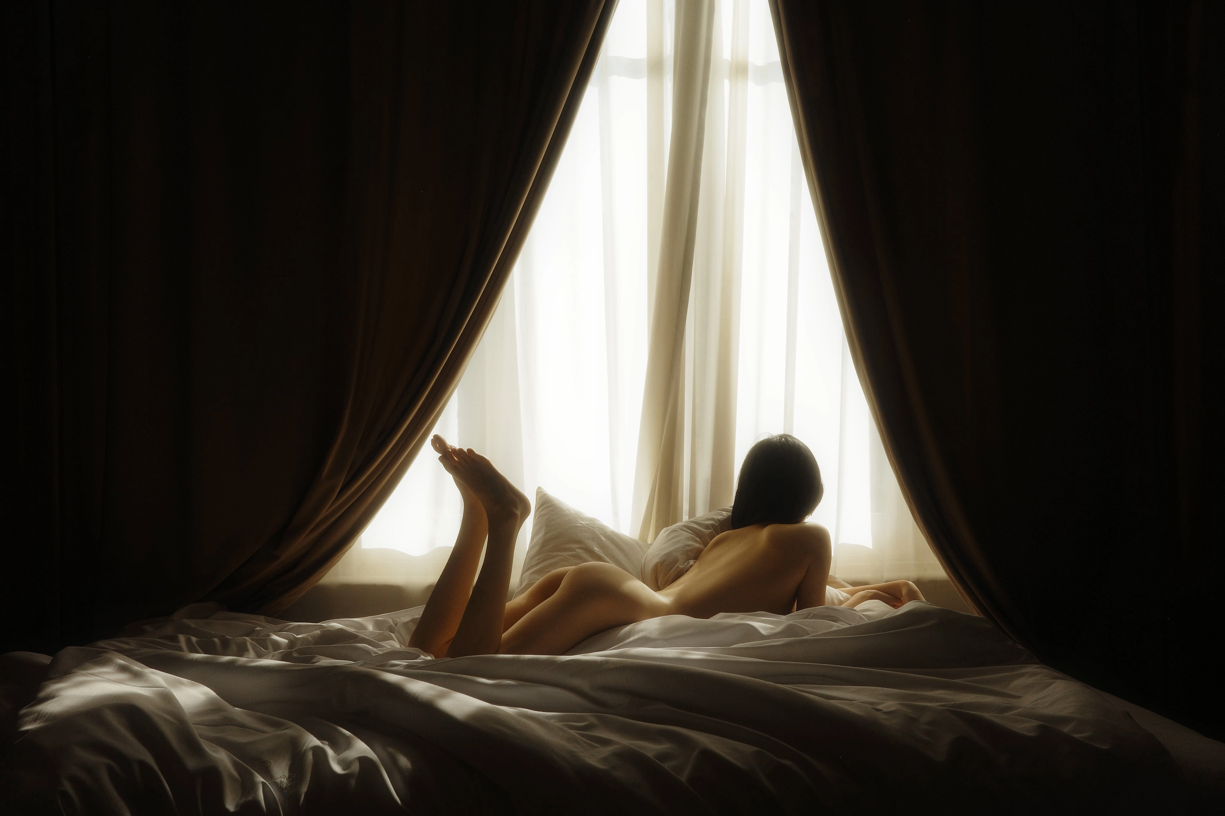 The woman lay on the bed, her legs stretched out.